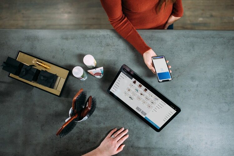 Person working at a desk using a smartphone and tablet to collaborate on a tech project