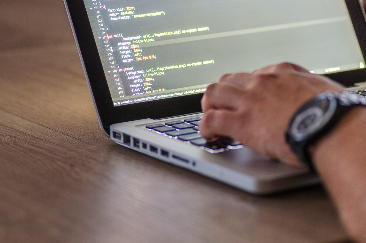 A developer working on a laptop with code on screen, symbolizing debugging a SharePoint App-Only authentication error.